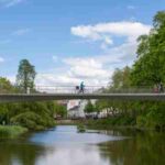 Cyclist crossing a bridge over a tranquil lake in Hamburg's Planten un Blomen park on a clear day. - Cyclist crossing a bridge over a tranquil lake in Hamburg's Planten un Blomen park on a clear day., tags: und - pexel